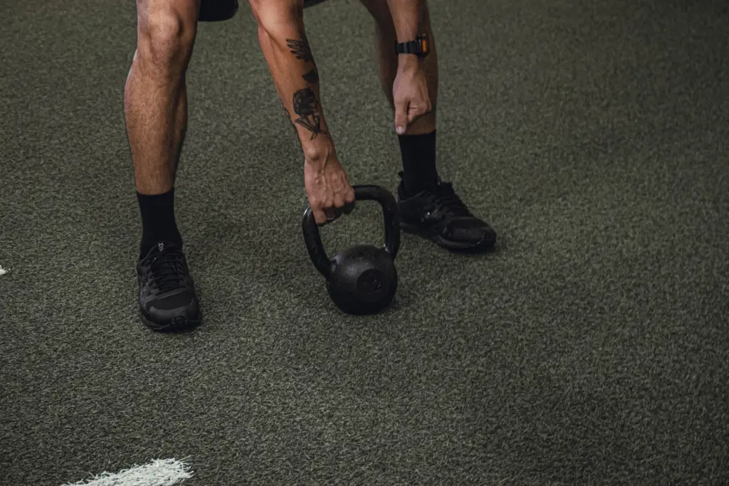 Homem treinando com kettlebell em estúdio de personal training, focando em força e técnica. Treino individualizado.