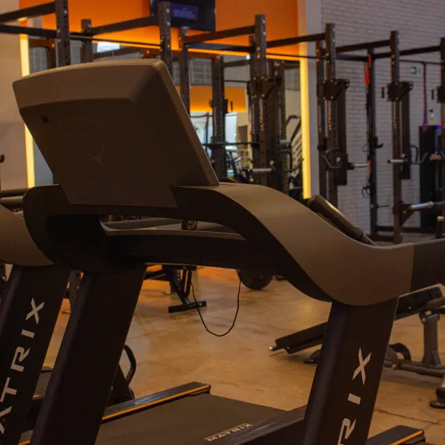 Academia moderna com esteiras Matrix e racks de força, ideal para personal training e treinos em grupo personalizados.