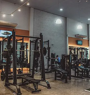 Interior moderno de estúdio de personal training com equipamentos de musculação, racks e bancos, ideal para treinos personalizados.