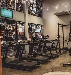 Academia moderna com esteiras e equipamentos de musculação para personal training e treinos em grupo personalizados.