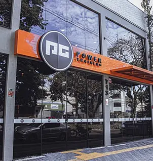 Fachada da clínica Power Training, estúdio de personal training e treinamento em grupo com grandes janelas e letreiro laranja.
